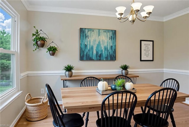 dining room featuring a chandelier, wood finished floors, ornamental molding, and baseboards