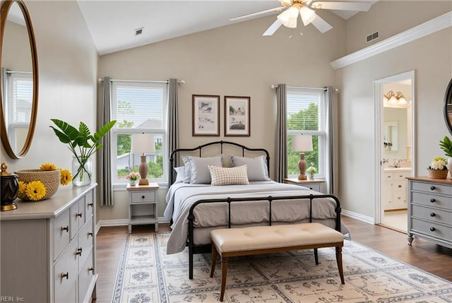 bedroom featuring multiple windows, light wood finished floors, ensuite bath, baseboards, and high vaulted ceiling