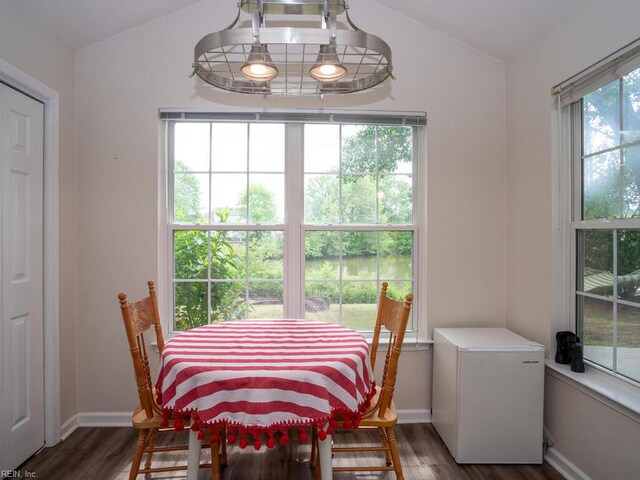 dining space featuring wood finished floors, lofted ceiling, and baseboards