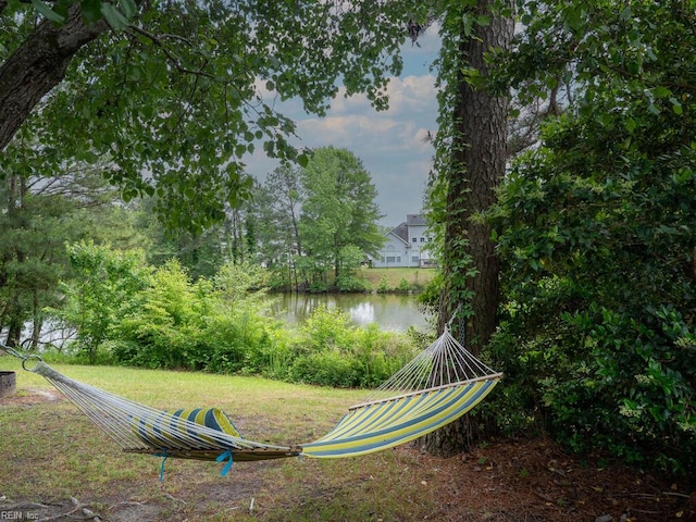 surrounding community with a water view and a lawn