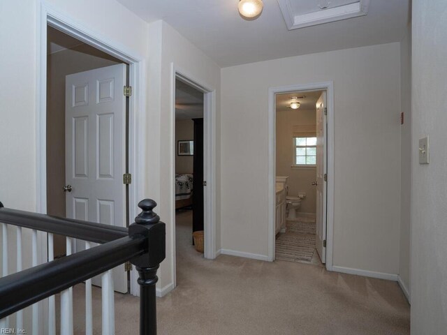 corridor featuring light carpet, baseboards, and an upstairs landing
