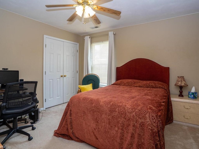bedroom with carpet floors, ceiling fan, a desk, and a closet