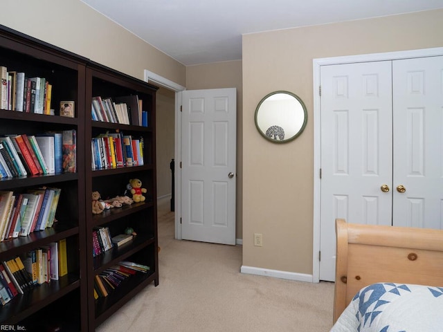 bedroom featuring light colored carpet, baseboards, and a closet