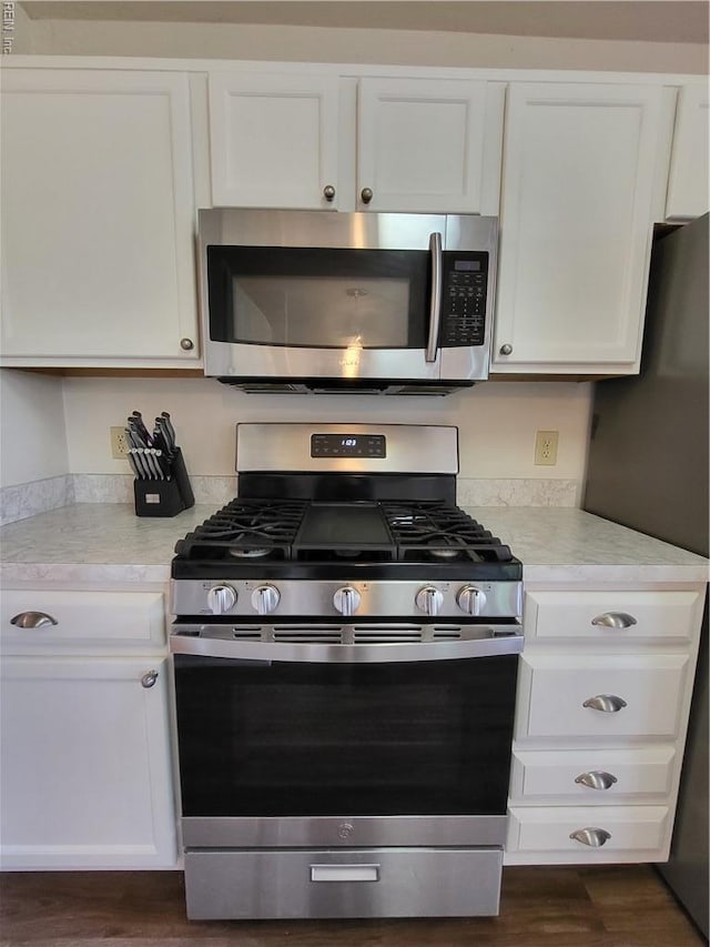 kitchen featuring appliances with stainless steel finishes, light countertops, white cabinets, and dark wood-type flooring
