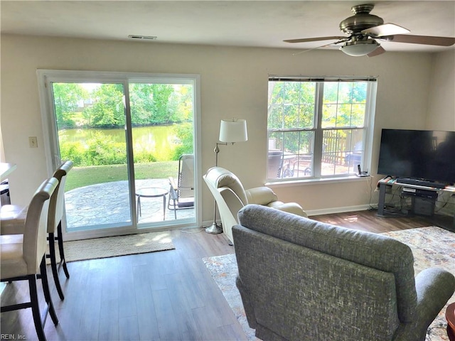 living area featuring a ceiling fan, wood finished floors, and baseboards