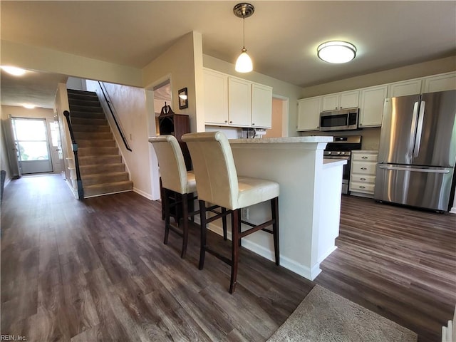 kitchen with appliances with stainless steel finishes, white cabinetry, dark wood-style floors, and light countertops