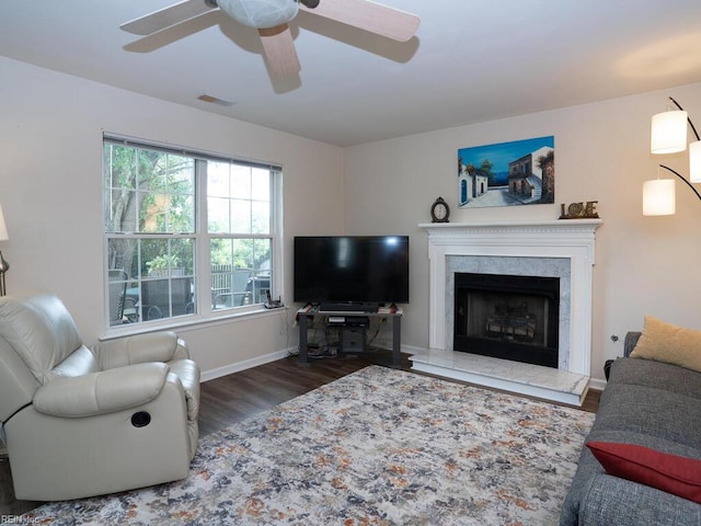 living area with wood finished floors, a ceiling fan, a premium fireplace, and baseboards