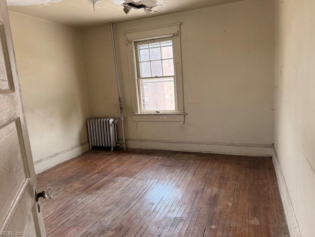 unfurnished room with radiator heating unit, hardwood / wood-style flooring, and baseboards