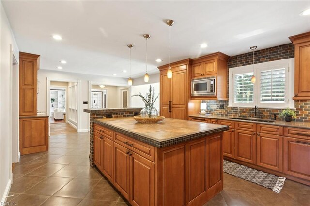 1276 Hebden Cv, Virginia Beach, VA 23452 - kitchen with a sink, stainless steel microwave, brown cabinetry, tasteful backsplash, and dark tile patterned flooring