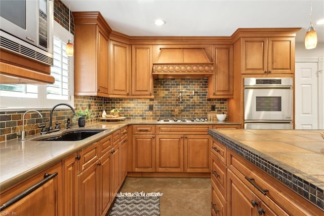 1276 Hebden Cv, Virginia Beach, VA 23452 - kitchen featuring a sink, appliances with stainless steel finishes, premium range hood, backsplash, and brown cabinetry