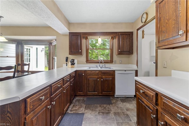 kitchen featuring dishwasher, a sink, healthy amount of natural light, light countertops, and a textured ceiling