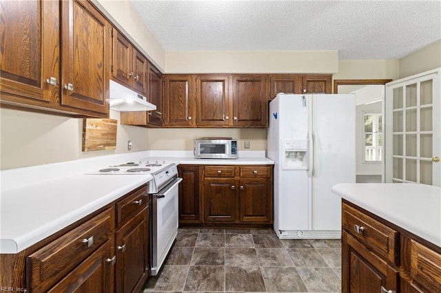 kitchen with white appliances, under cabinet range hood, light countertops, and a textured ceiling