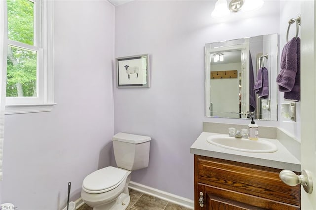 bathroom with toilet, vanity, tile patterned floors, and baseboards