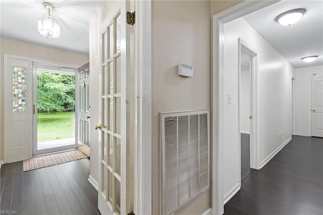 corridor featuring dark wood finished floors, baseboards, and a textured ceiling