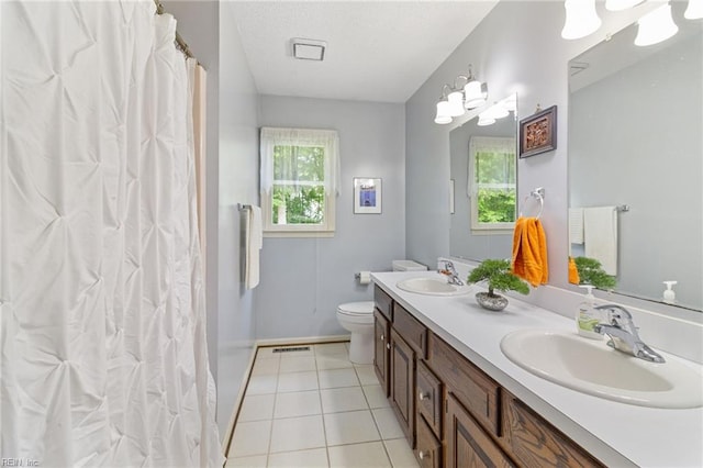 bathroom with plenty of natural light, toilet, baseboards, double vanity, and a textured ceiling