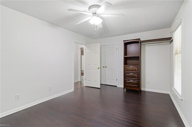 unfurnished bedroom with dark wood-style floors, a textured ceiling, baseboards, and a ceiling fan