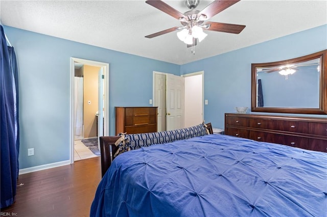 bedroom with baseboards, wood finished floors, ensuite bathroom, and a ceiling fan