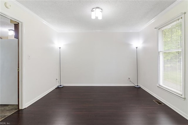 spare room with a textured ceiling, dark wood-style floors, ornamental molding, and baseboards