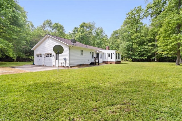 ranch-style house featuring a front yard, a chimney, a garage, and view of wooded area