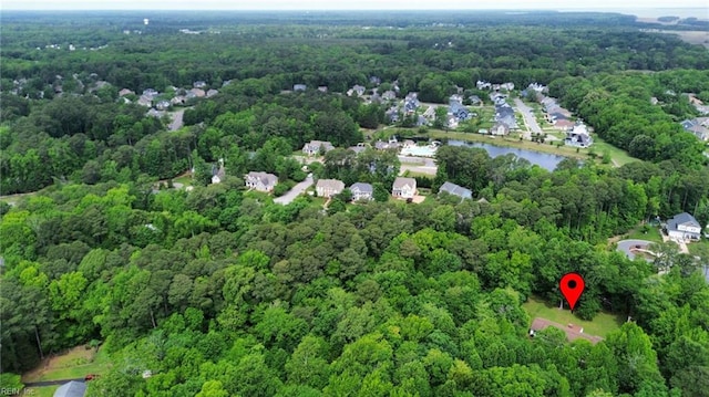 view of property location featuring a forest and a nearby body of water