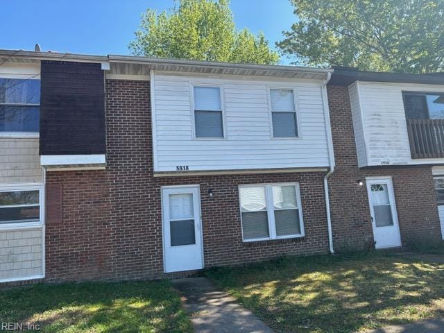 townhome / multi-family property featuring brick siding and a front lawn