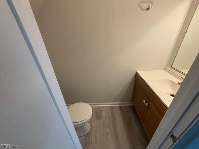bathroom featuring vanity, wood finished floors, toilet, and baseboards