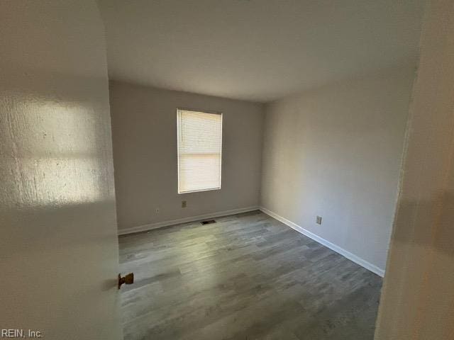 spare room featuring baseboards and wood finished floors