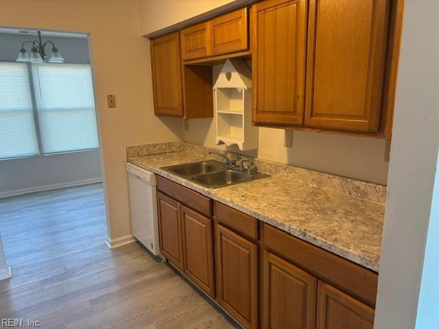 kitchen with a sink, dishwasher, light wood-style flooring, and brown cabinetry