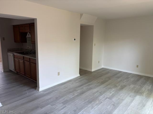 unfurnished room featuring wood finished floors, baseboards, and a sink