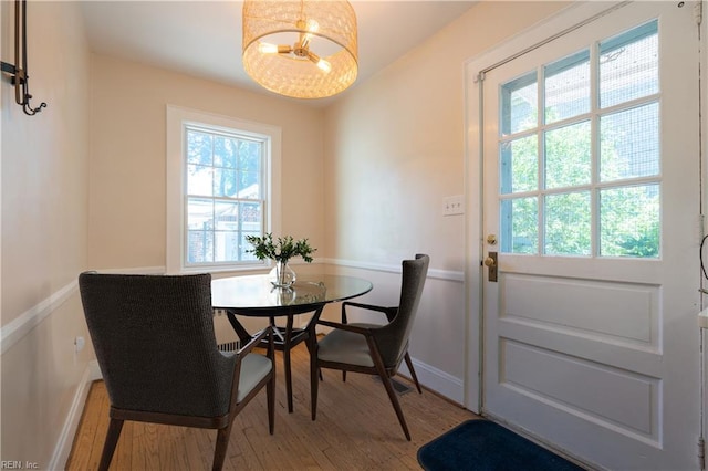 dining room featuring light wood-style floors, healthy amount of natural light, baseboards, and a chandelier