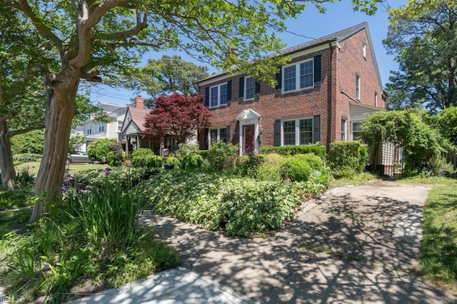 colonial-style house featuring brick siding and a gate