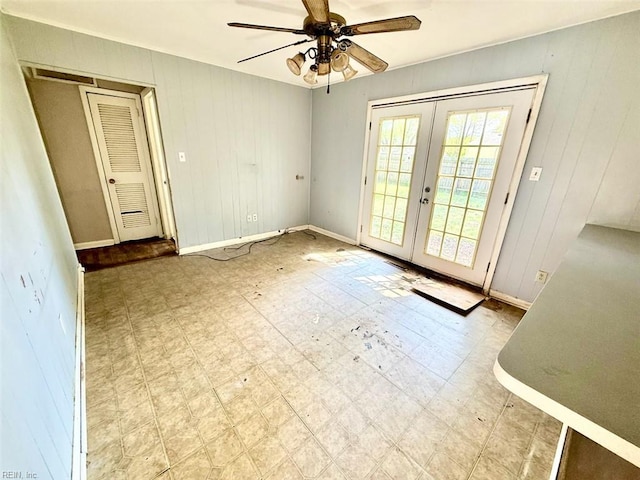 doorway with french doors, a ceiling fan, tile patterned floors, wooden walls, and baseboards