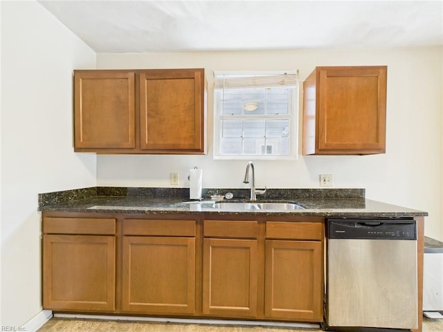 kitchen with stainless steel dishwasher, a sink, dark stone counters, and brown cabinetry