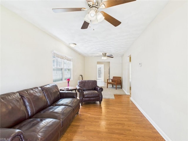 living room with ceiling fan, light wood finished floors, and baseboards
