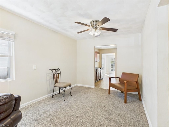 living area featuring light carpet, ceiling fan, and baseboards