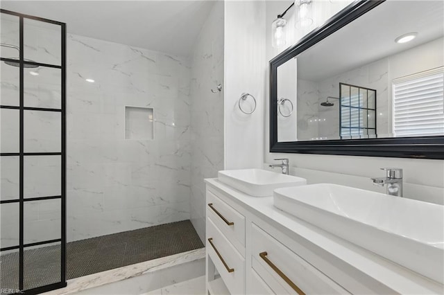 bathroom featuring a marble finish shower, marble look tile flooring, and double vanity