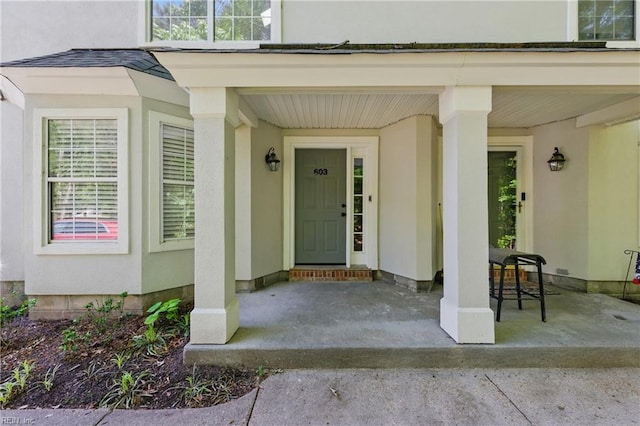 view of exterior entry featuring stucco siding and covered porch