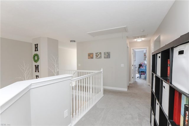 corridor with attic access, light carpet, and baseboards