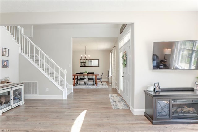 entryway featuring stairway, wood finished floors, a chandelier, and baseboards