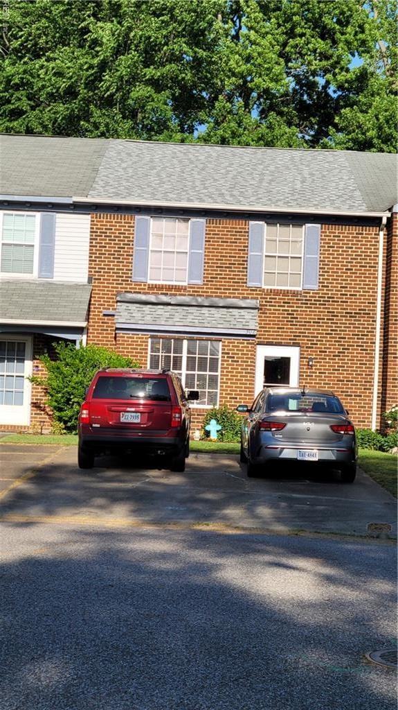 view of front of home featuring brick siding and roof with shingles