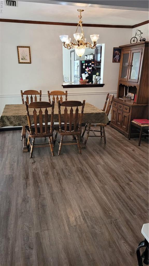 dining area featuring crown molding, dark wood-style flooring, and a chandelier