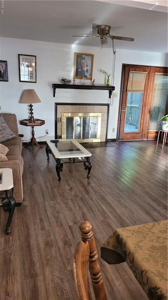 living room with a ceiling fan, wood finished floors, and a tile fireplace