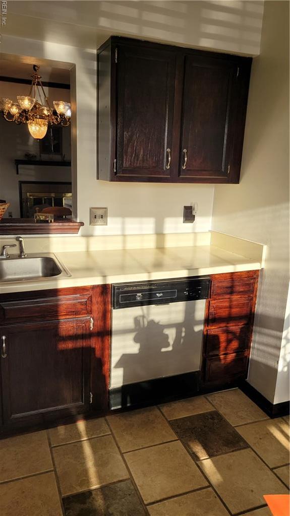 kitchen featuring dishwasher, a sink, a chandelier, light countertops, and baseboards