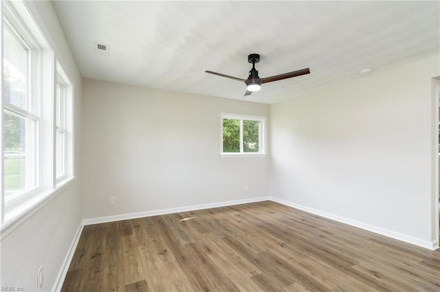 unfurnished room with wood finished floors, a ceiling fan, and baseboards