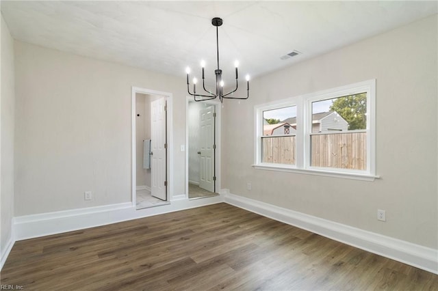 unfurnished dining area with a chandelier, wood finished floors, and baseboards