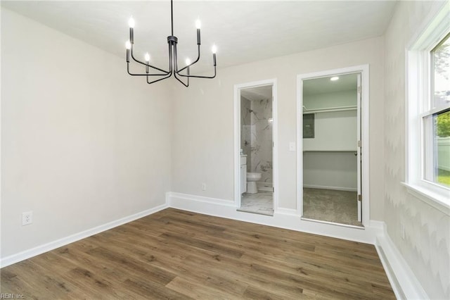 unfurnished dining area featuring a chandelier, wood finished floors, and baseboards