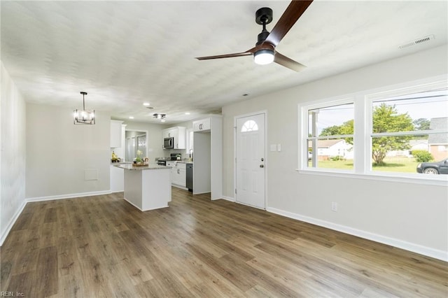 unfurnished living room with baseboards, a chandelier, a ceiling fan, wood finished floors, and recessed lighting