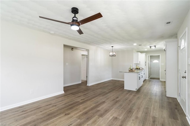 unfurnished living room with baseboards, wood finished floors, and ceiling fan