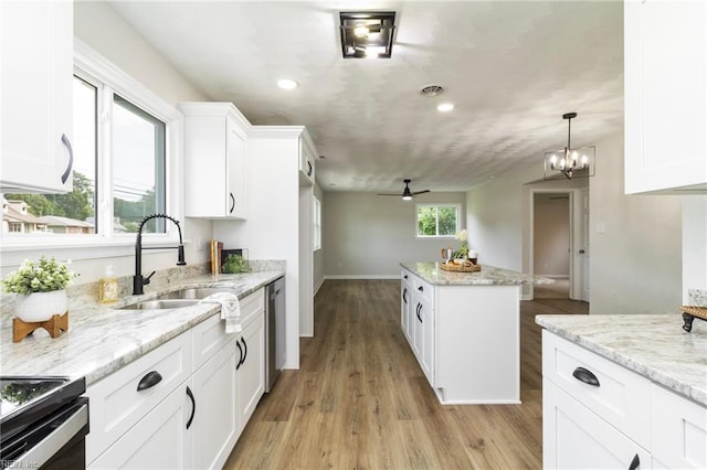 kitchen featuring a sink, a kitchen island, ceiling fan, light wood-type flooring, and white cabinets