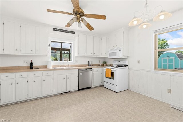 kitchen with white appliances, light floors, a sink, light countertops, and white cabinetry